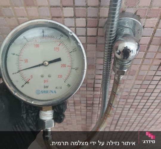 מד לחץ מים מחובר לצינור במקלחת